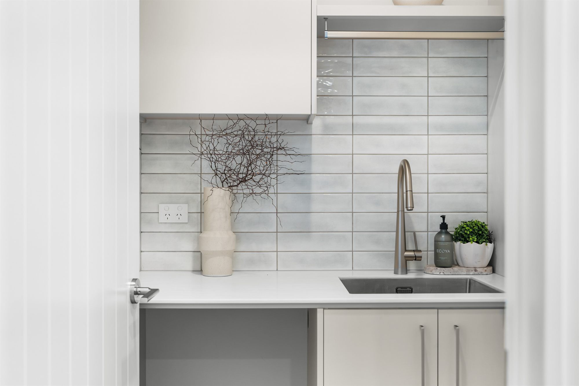 Separate tiled laundry with sink and cabinetry