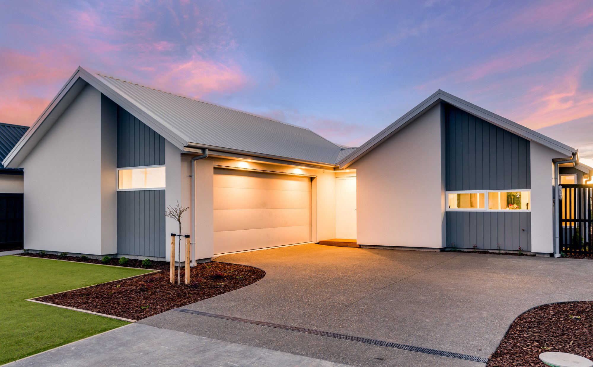 An Elmbridge Mews home at dusk — gabled roofline, double garage, on Waianiwa Place